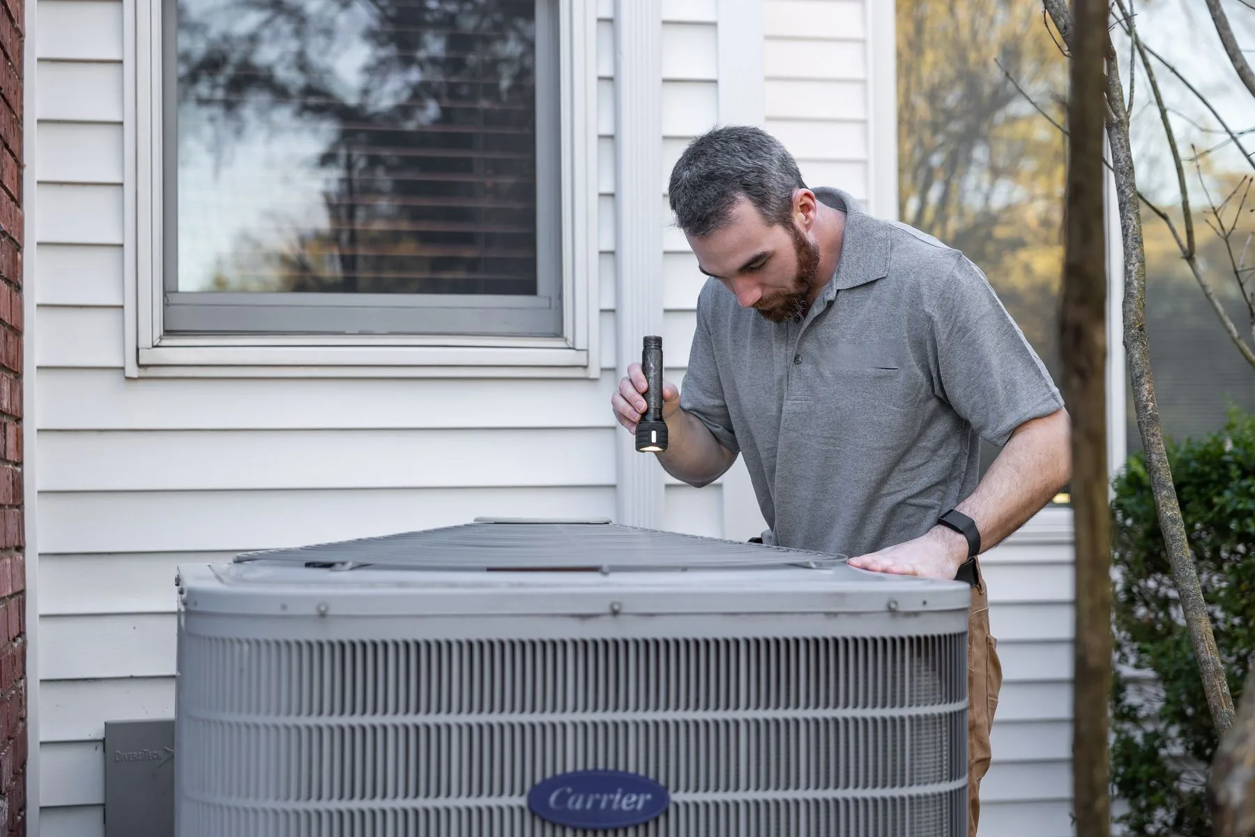 HVAC technician inspecting an outdoor unit at a residential home