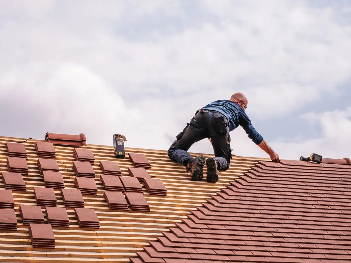 Roofing contractor installing tiles on a residential roof